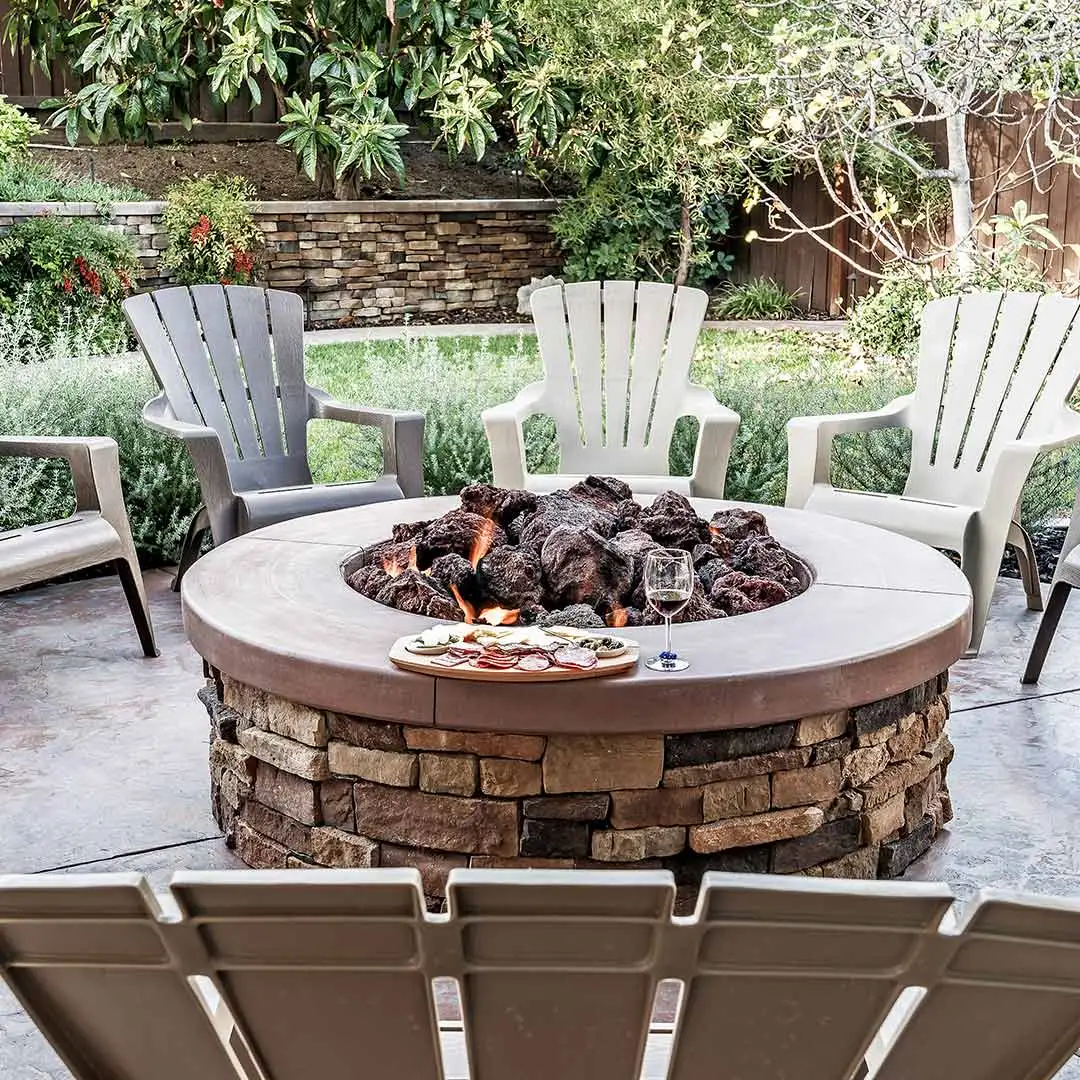 A brand fire pit surrounded by seats with a food platter and glass of wine in Matthews, NC.