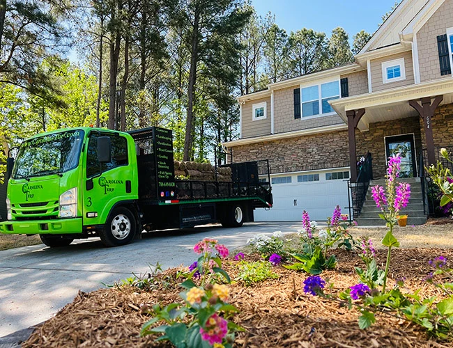 Beautiful landscape bed freshly installed with a Carolina Turf Lawn and Landscape company truck in the driveway.