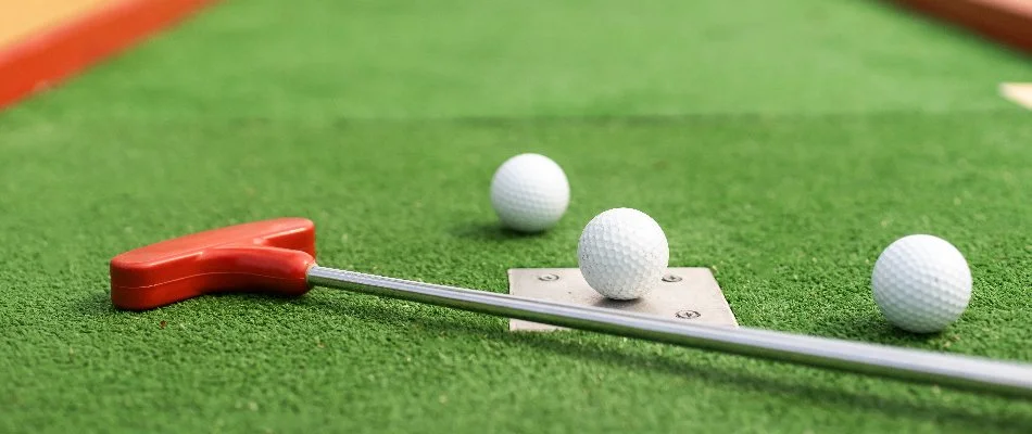 Artificial turf in Matthews, NC, with a golf club and balls.