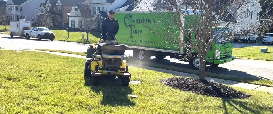 A lawn care professional in Matthews, NC, using equipment to provide lawn care after a grub infestation.