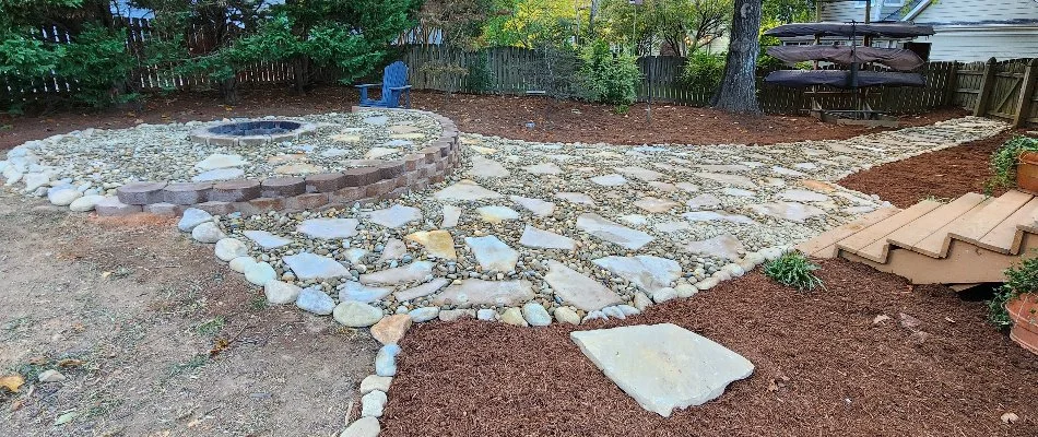 Backyard fire pit with rocks and a stone walkway in Matthews, NC.